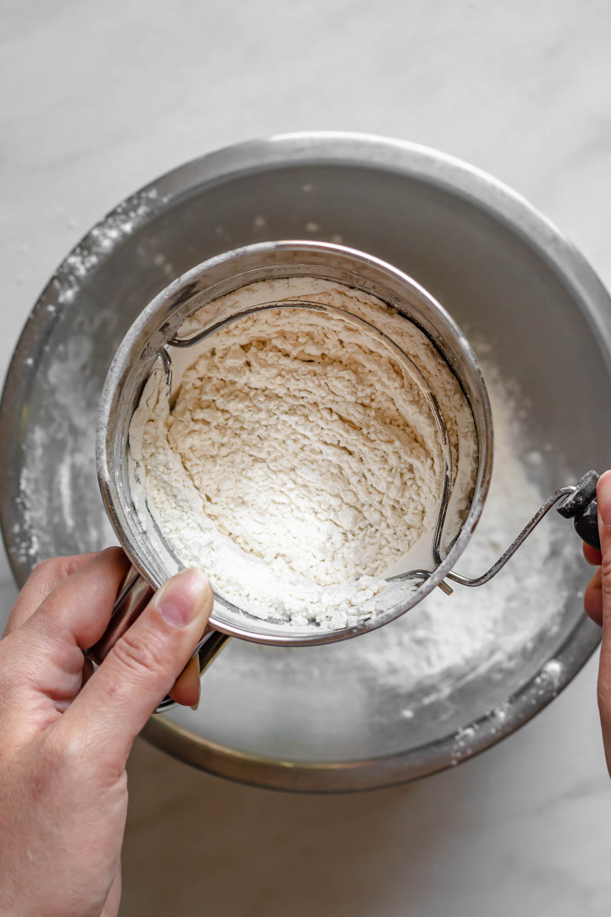 Sifting flour into a bowl.