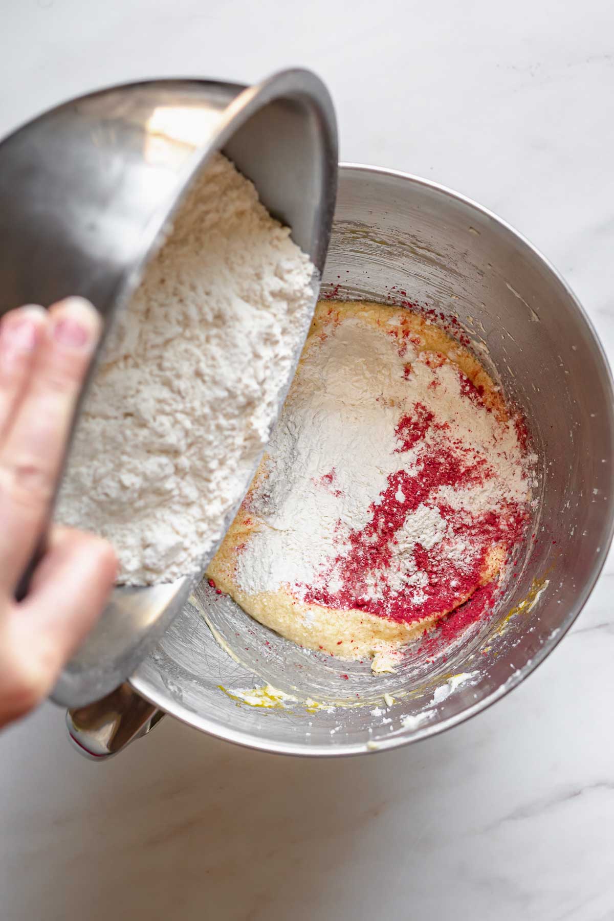 Flour getting poured into strawberry cake batter.