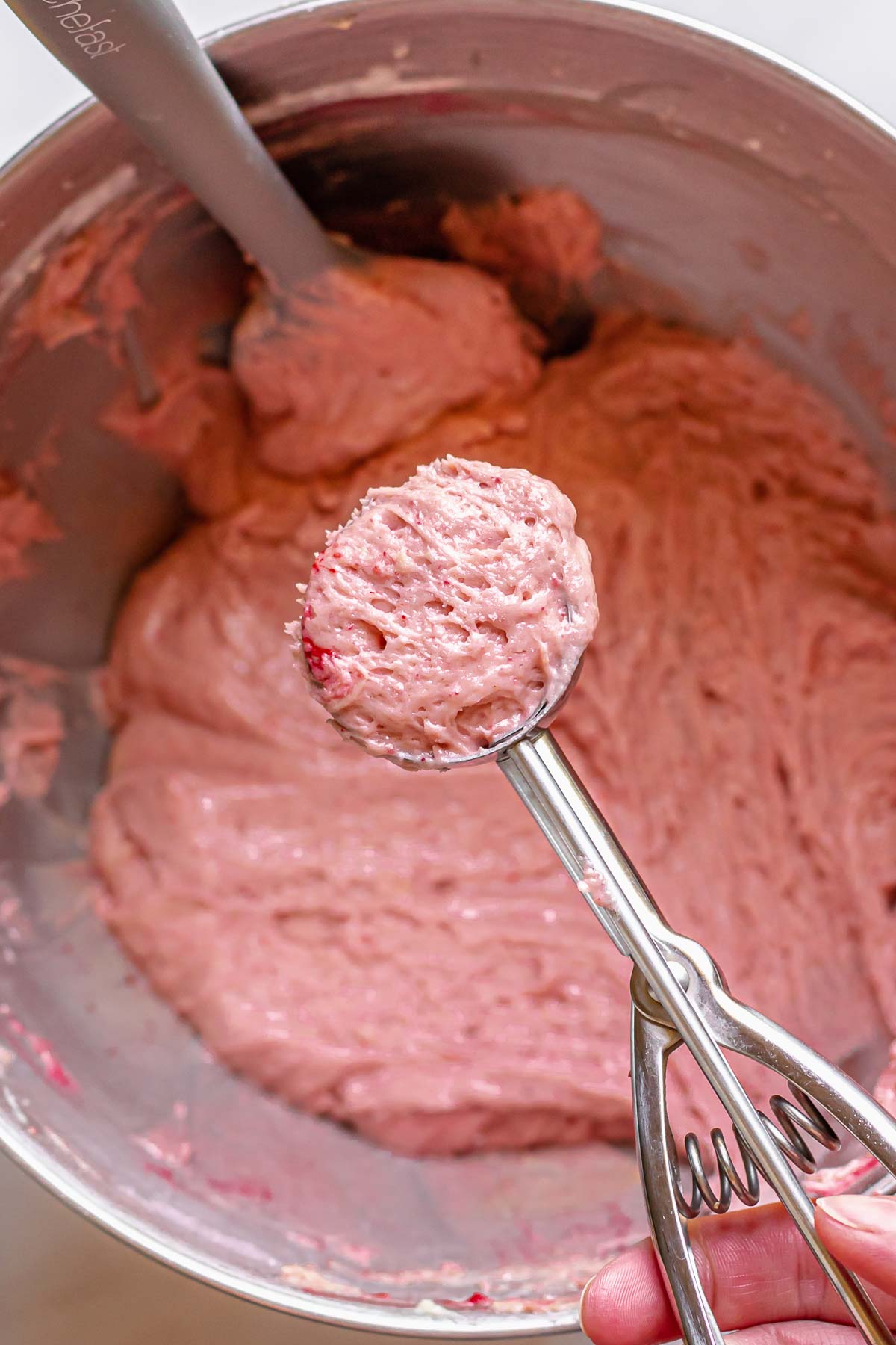 A scoop of strawberry cake batter in a cookie scoop.
