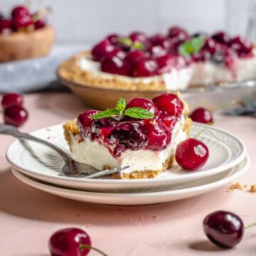 Slice of no bake cherry cheesecake pie on a plate with a bite removed.