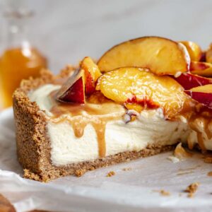 Sliced no bake mascarpone cheesecake on a platter with peaches on top.