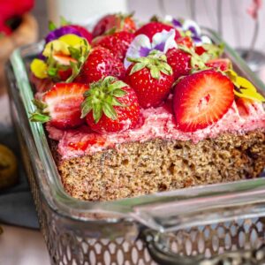 Strawberry banana cake decorated in a loaf pan with a slice removed.