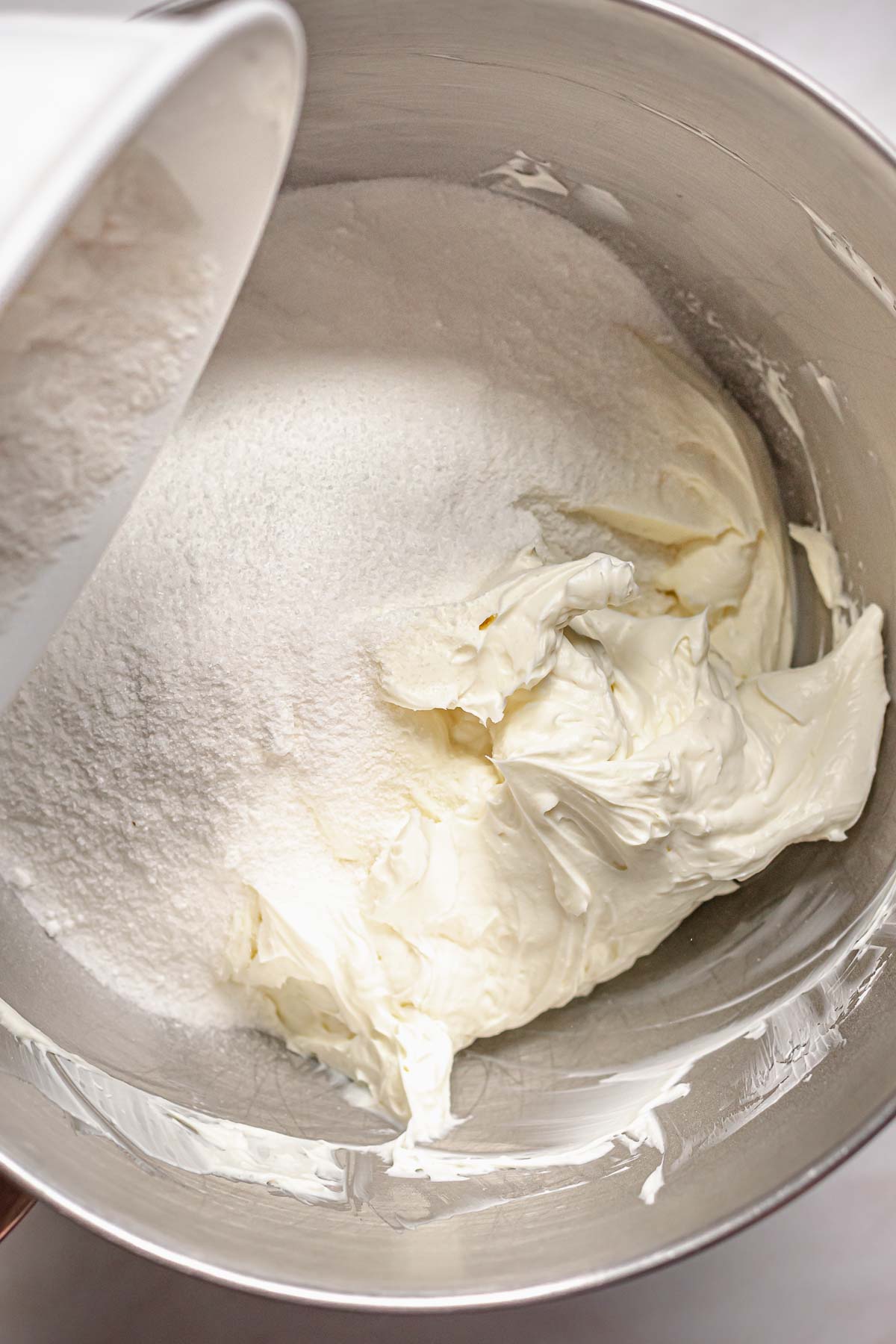 Adding sugar to cream cheese.