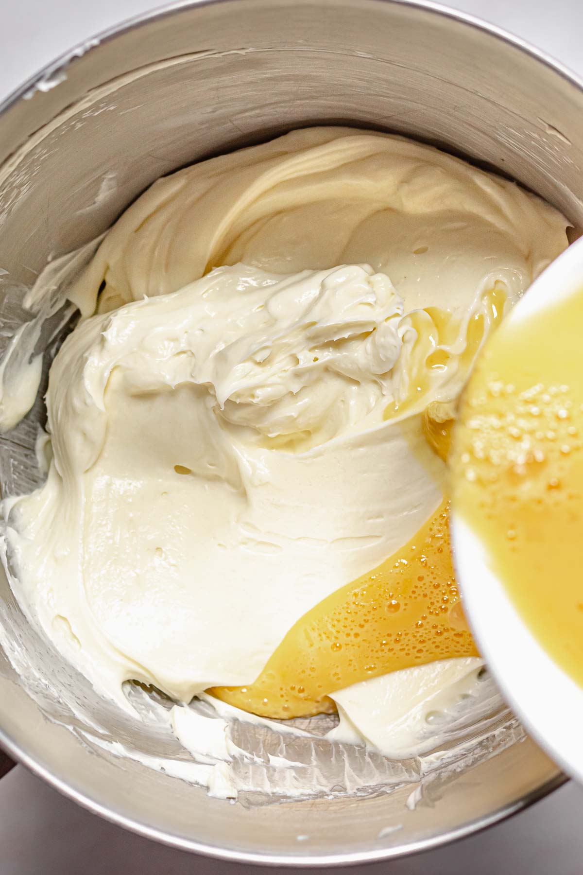 Adding whipped eggs to chocolate marble cheesecake batter.