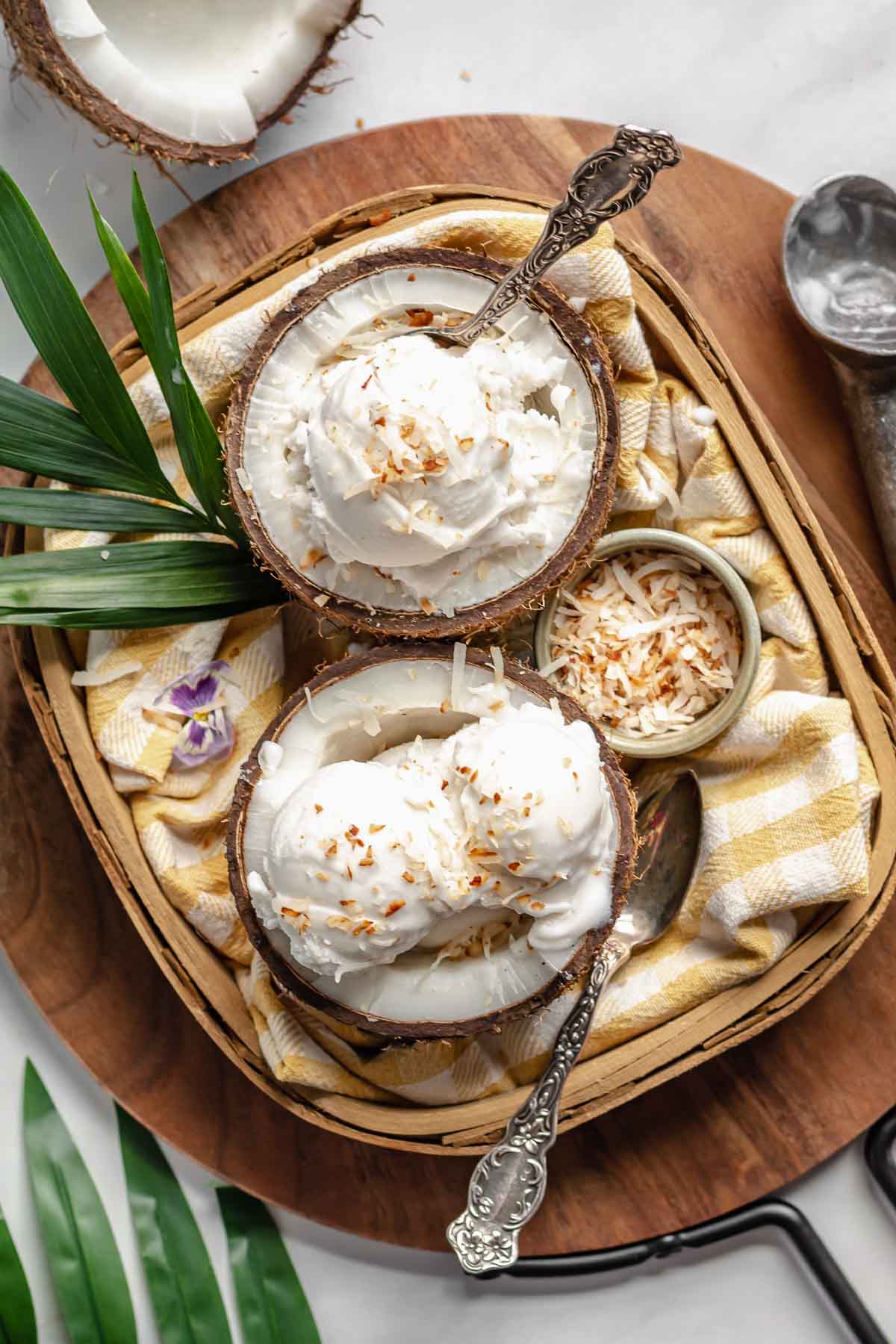 Two coconut shells in a basket filled with coconut sorbet.