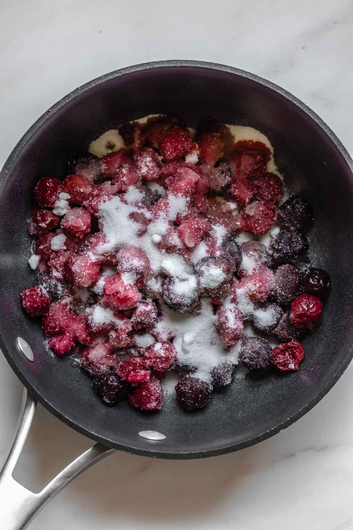 Cherries and sugar in a saucepan.