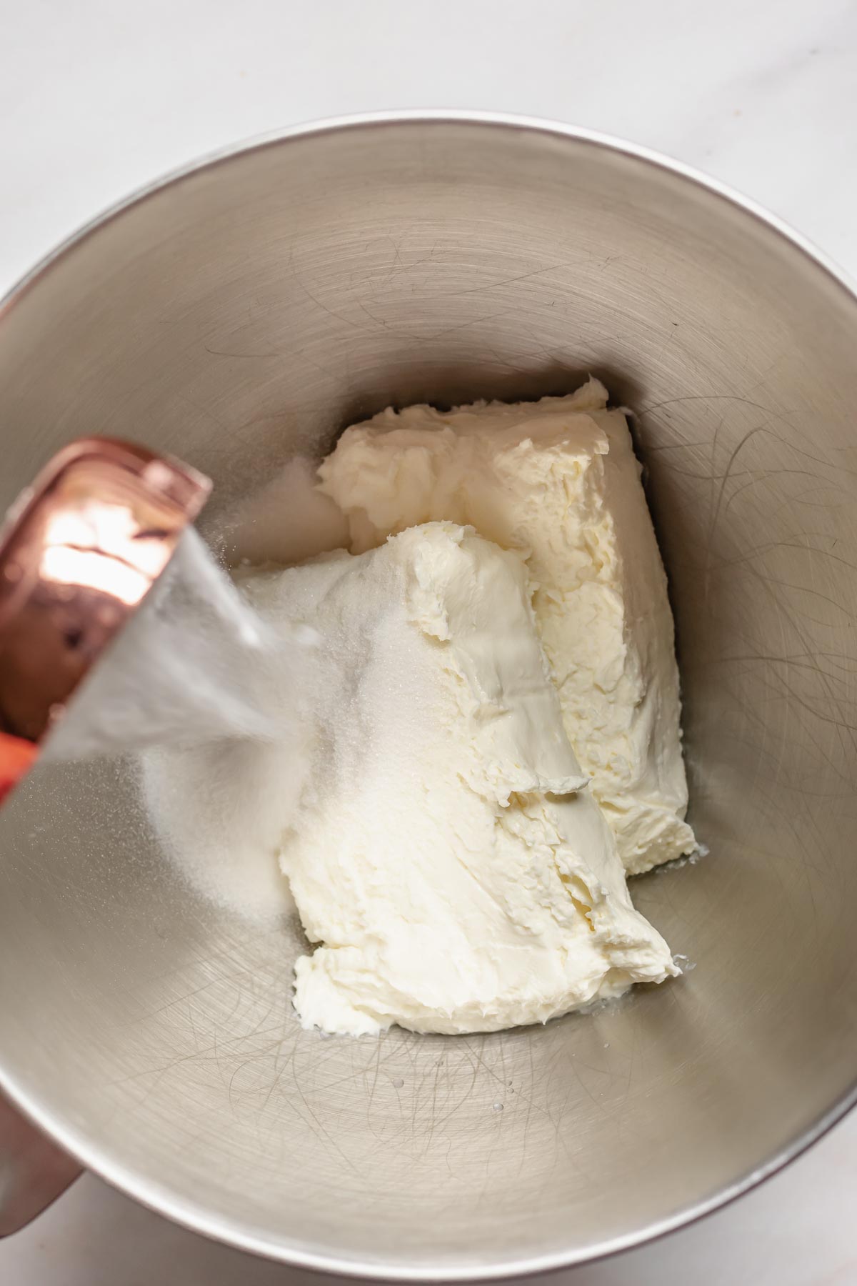 Sugar and cream cheese in the bowl of a stand mixer.