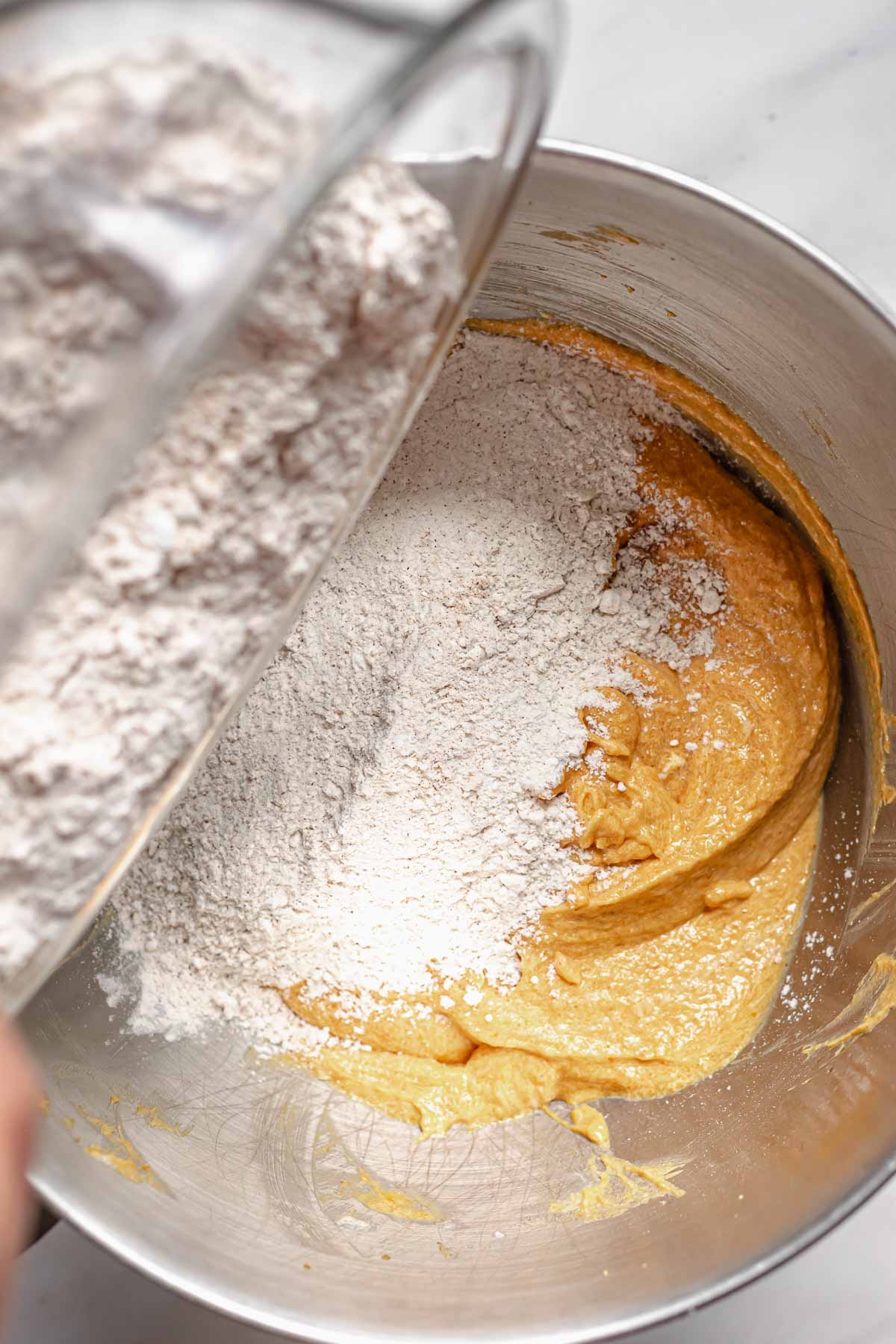 Flour mixture being added to the batter in a bowl.