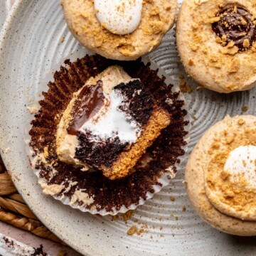 Graham cracker cupcakes on a plate. One is cut in half laying on the liner.