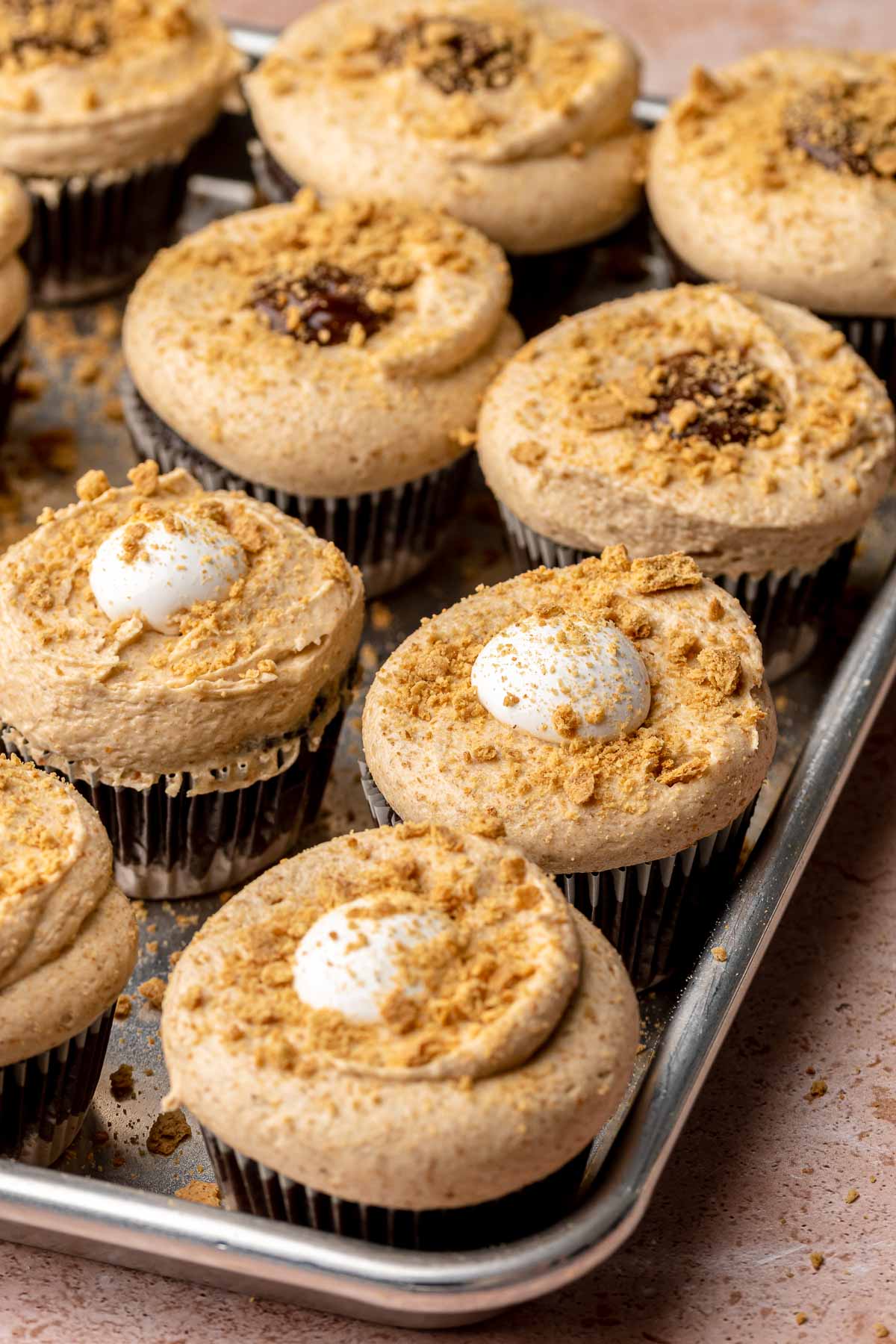 Fully decorated smores cupccakes on a cookie sheet.