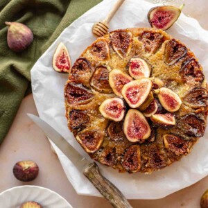 Fig cake on a platter with fresh figs and honey.