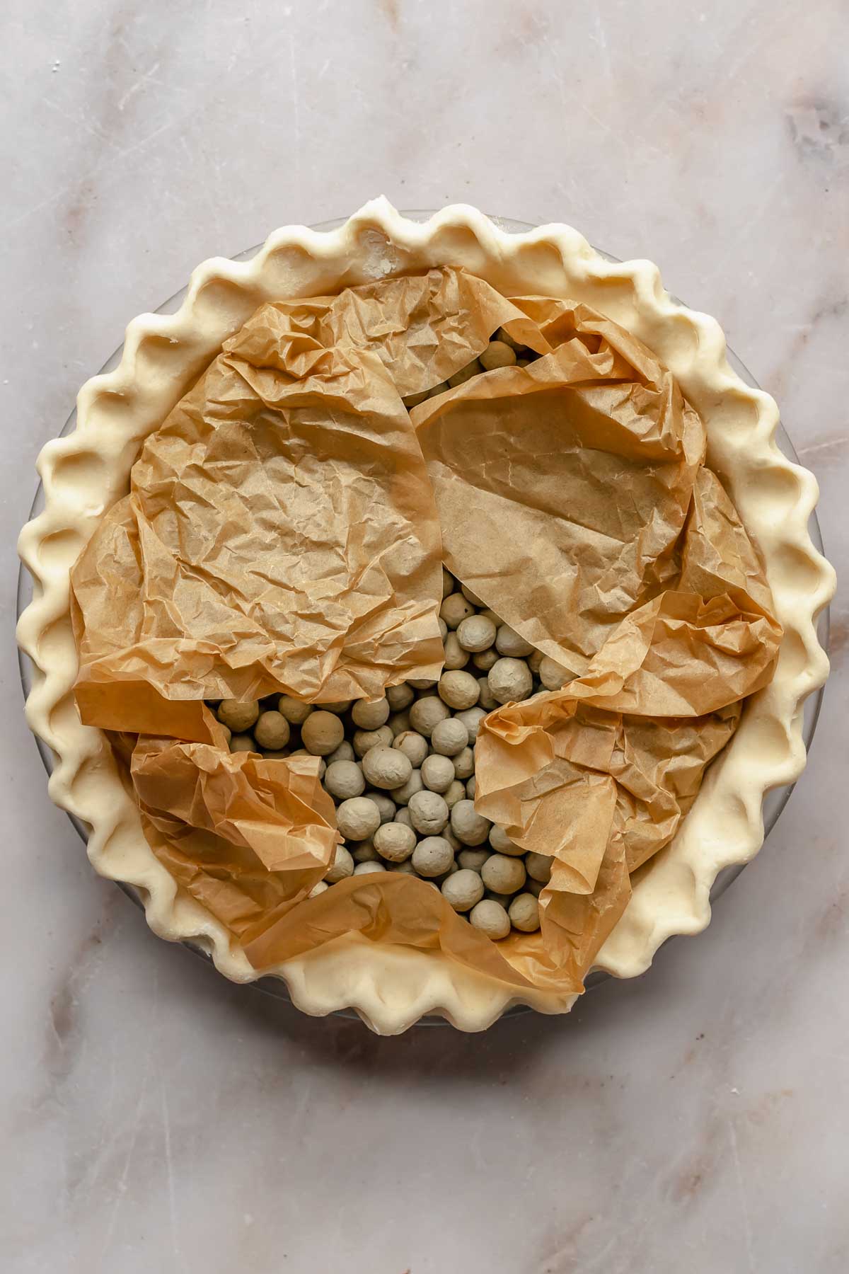 Pie crust filled with parchment paper and pie weights.