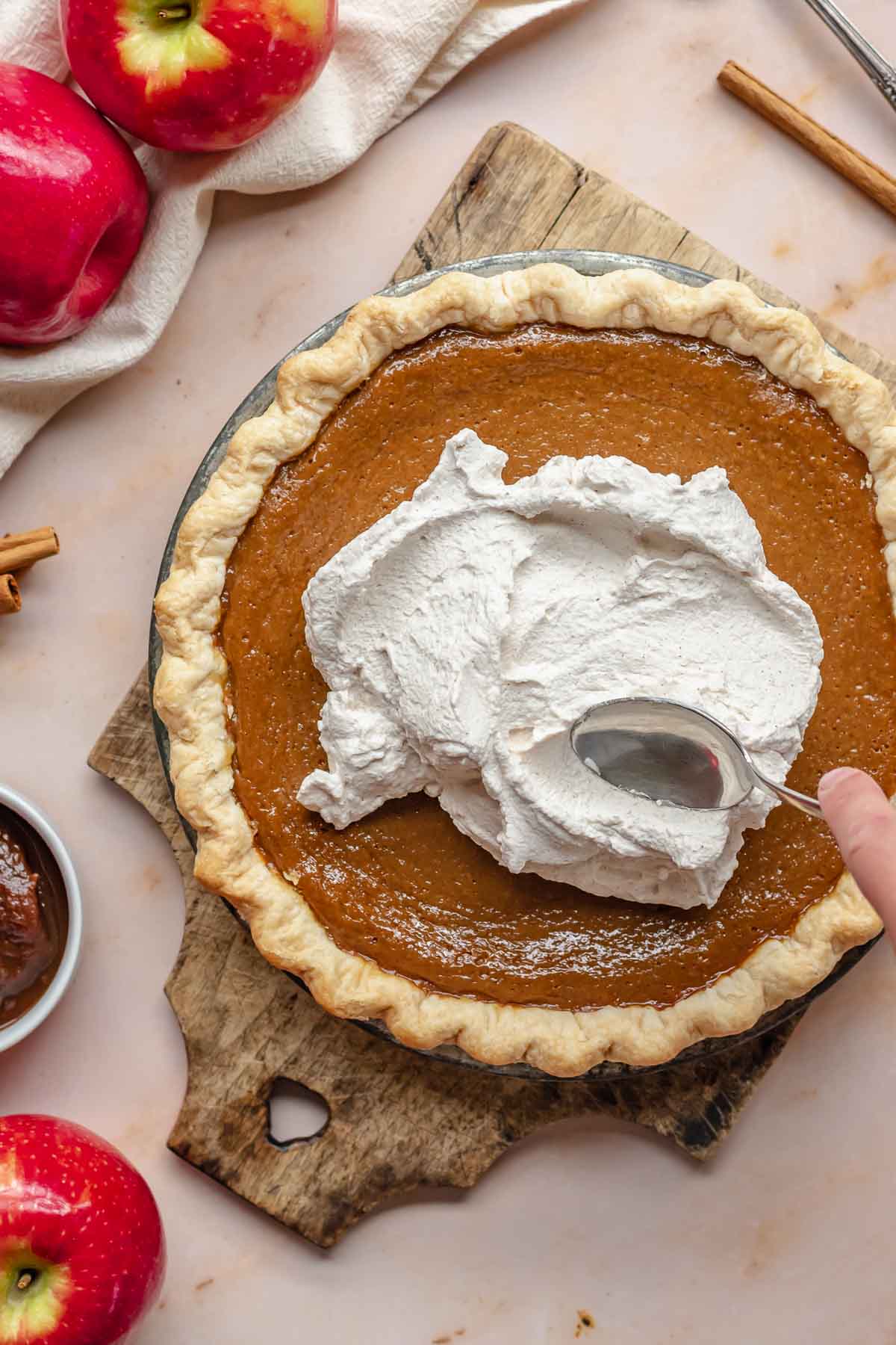A spoon swooping cinnamon whipped cream on apple butter pie.