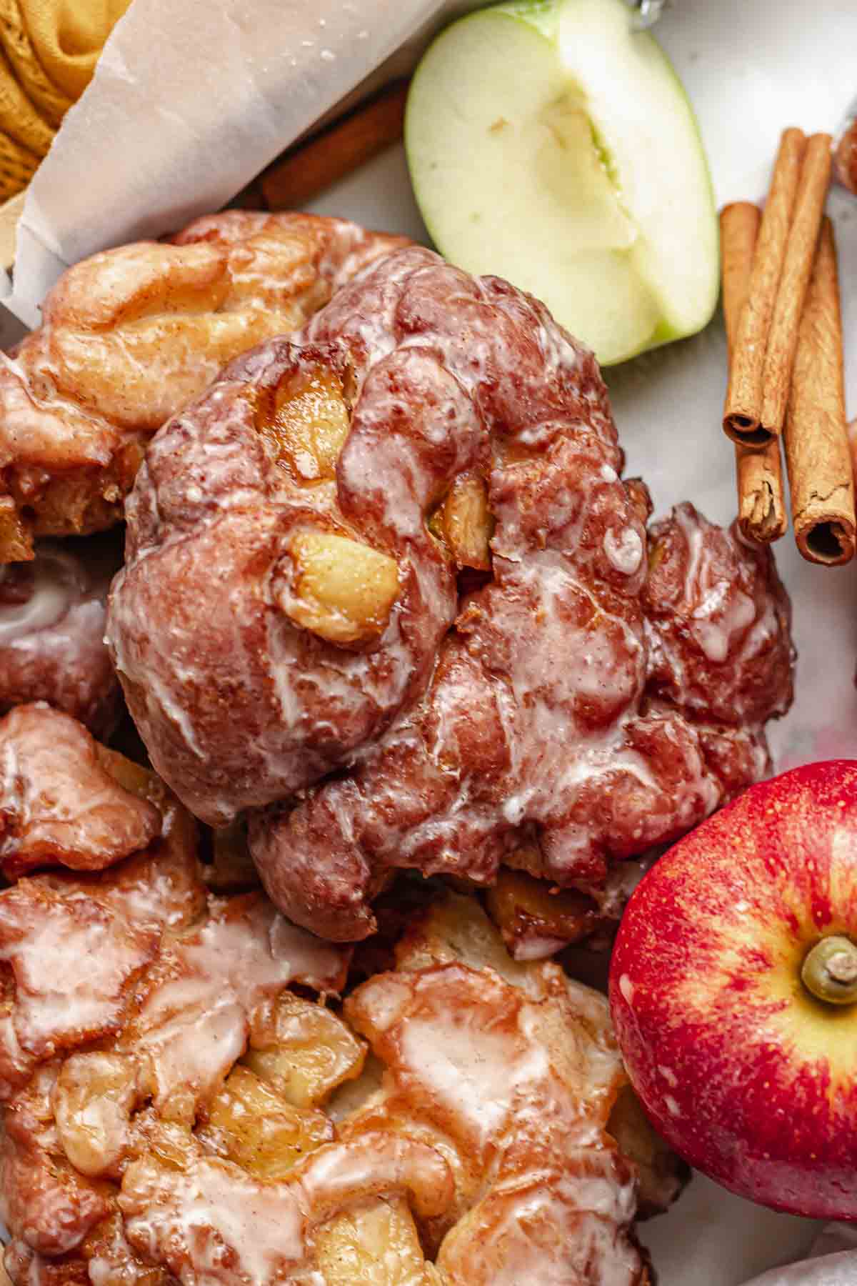 Apple fritter donut in a basked with apples and cinnamon sticks.