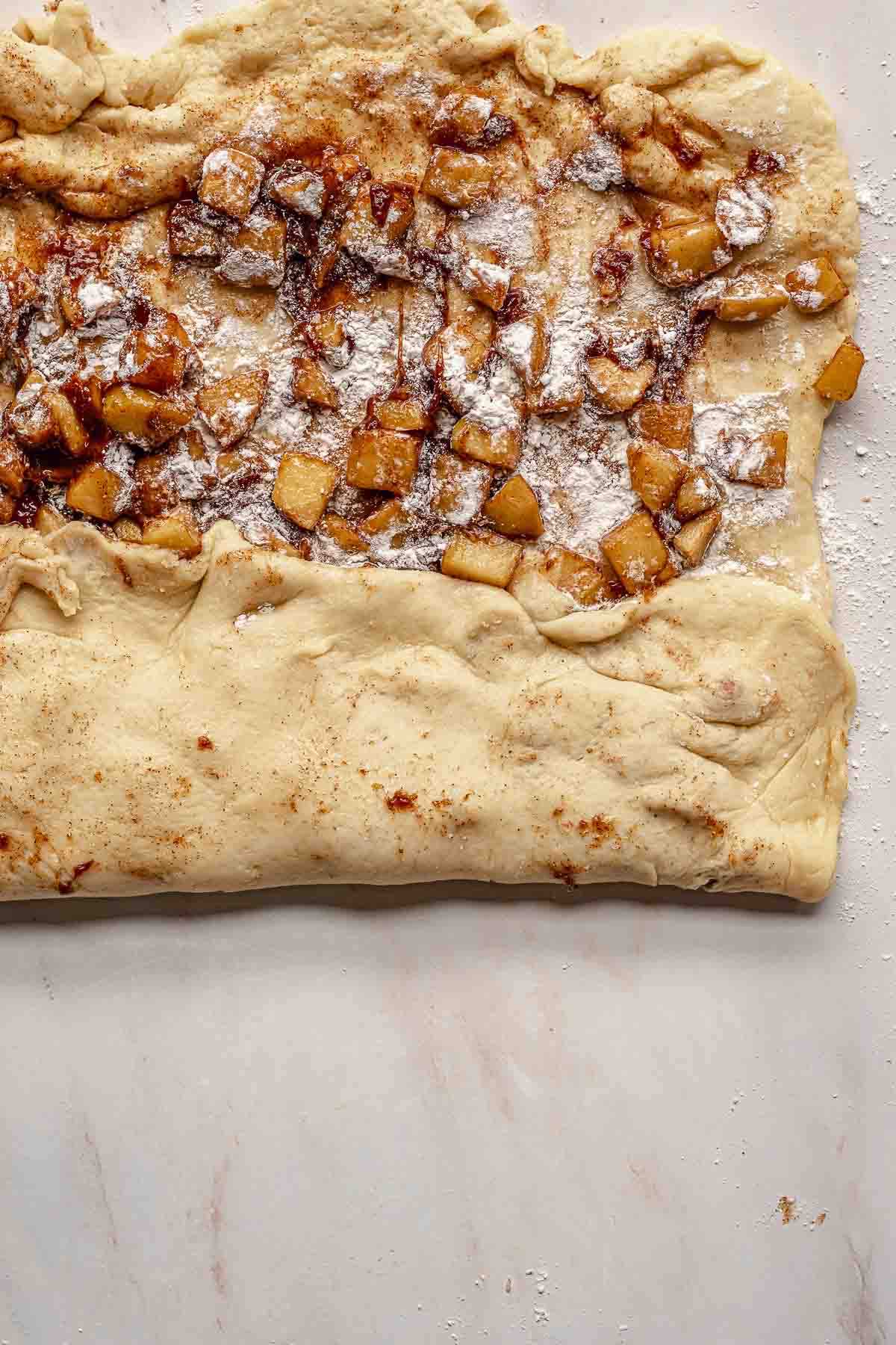 The dough folds into thirds to enclose the apples.