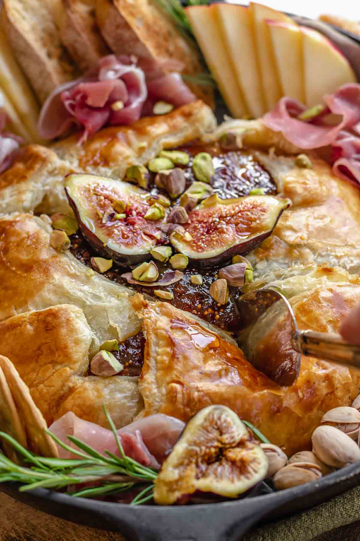 Slicing into a baked brie with figs on top.
