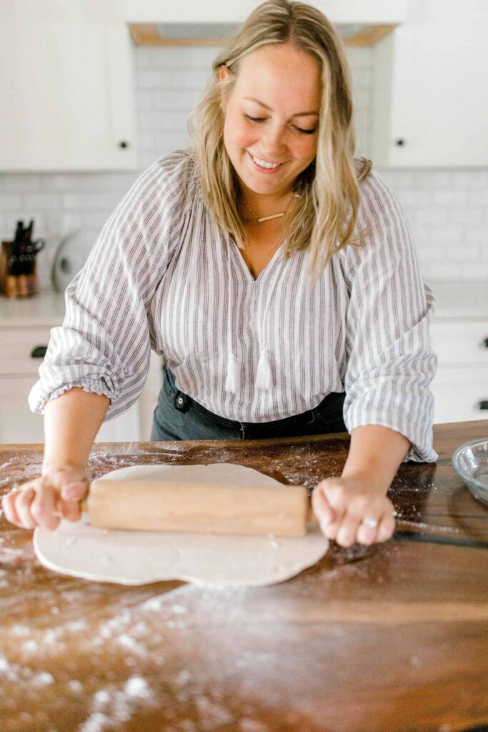 Rolling out pie dough on a counter.