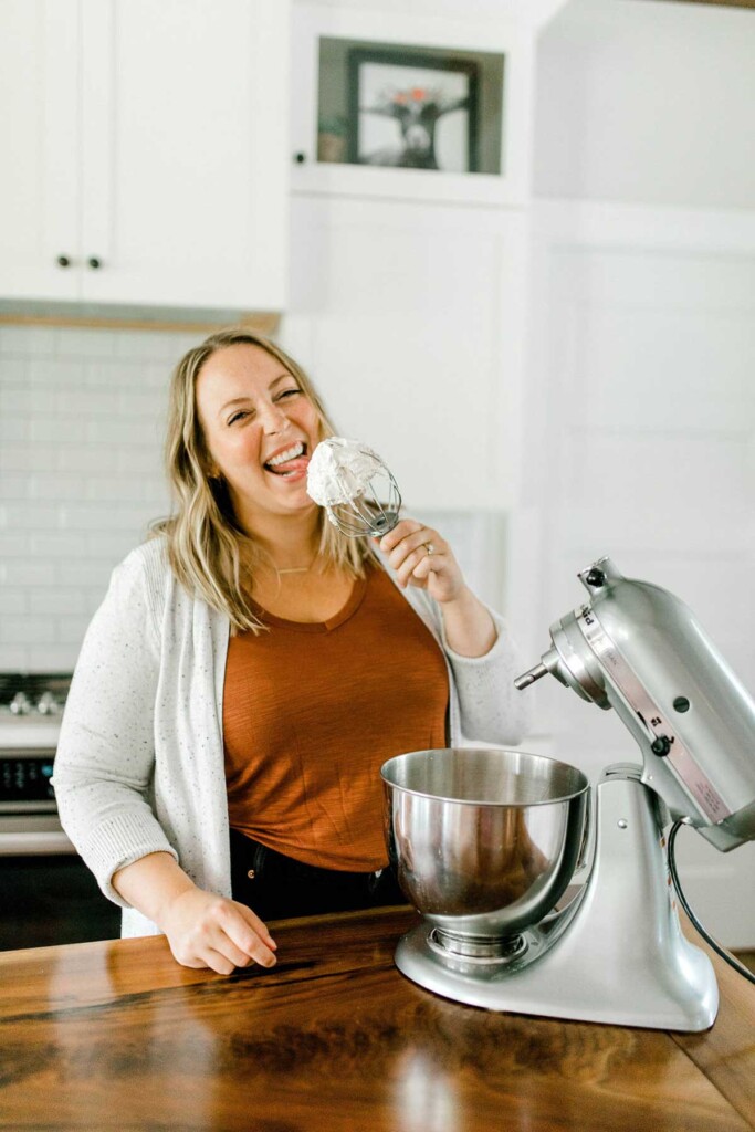 Licking a whisk with whipped cream.