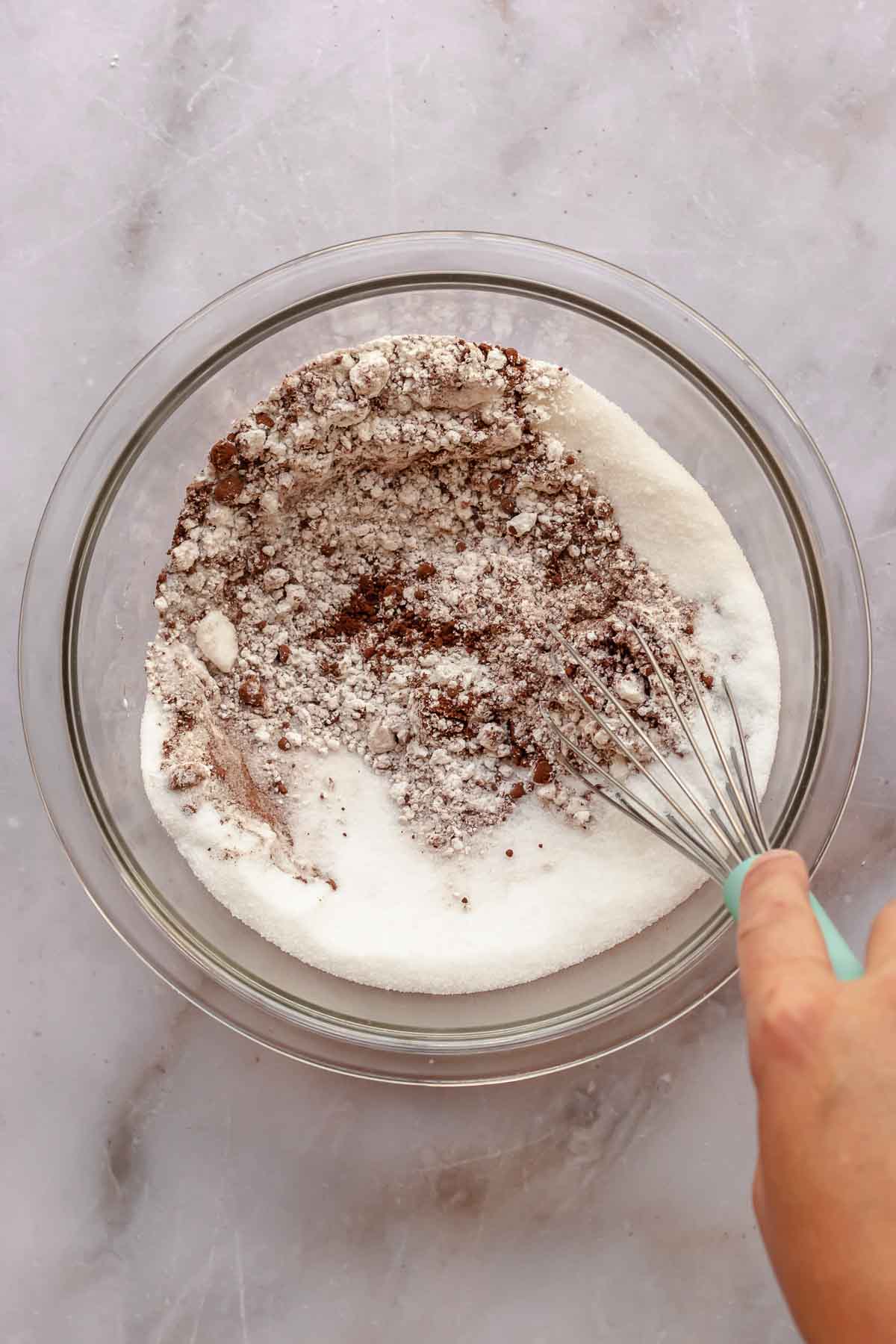A whisk mixes together the dry cupcake ingredients in a bowl.