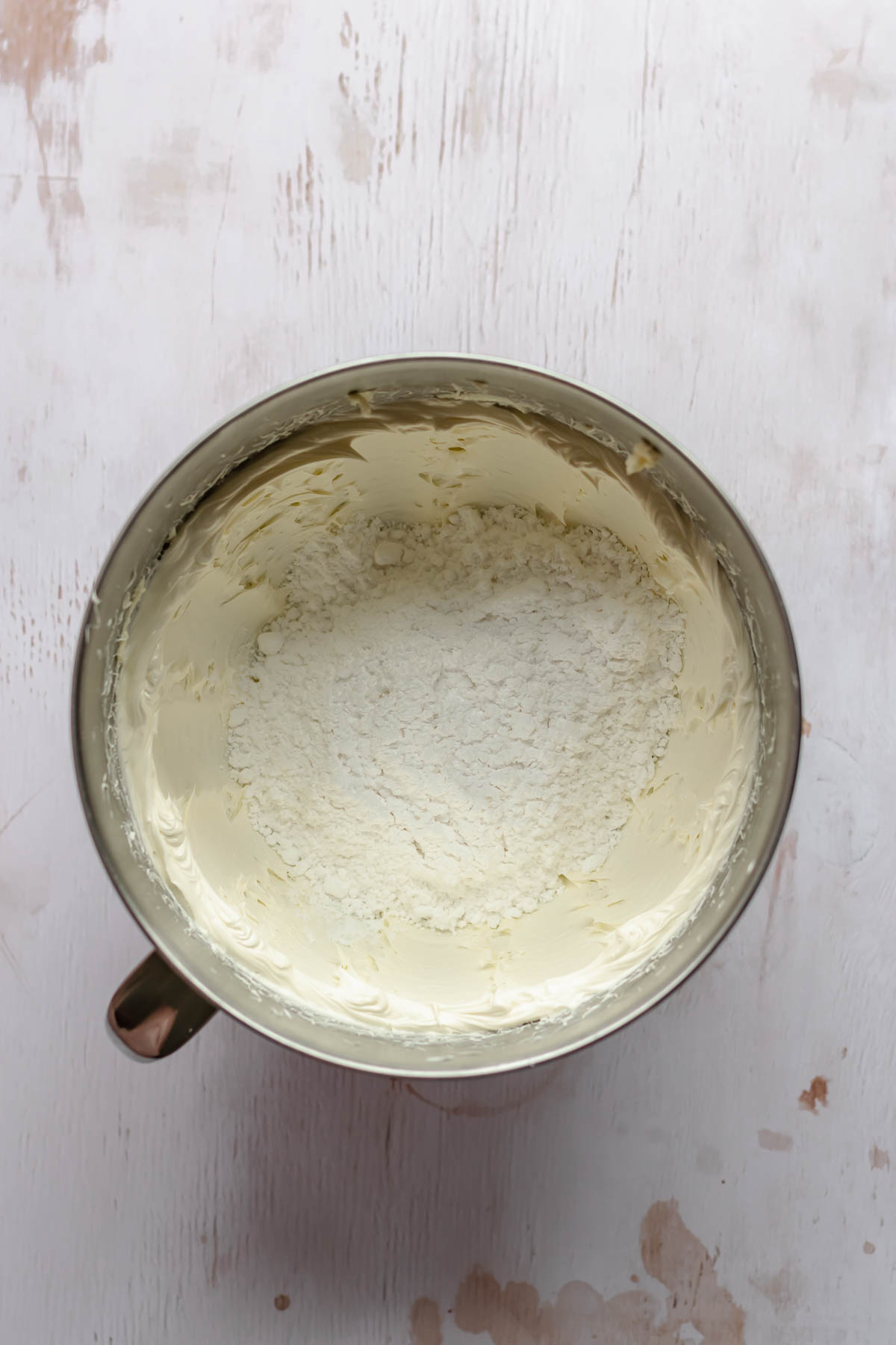 Creamed butter in a bowl with powdered sugar.