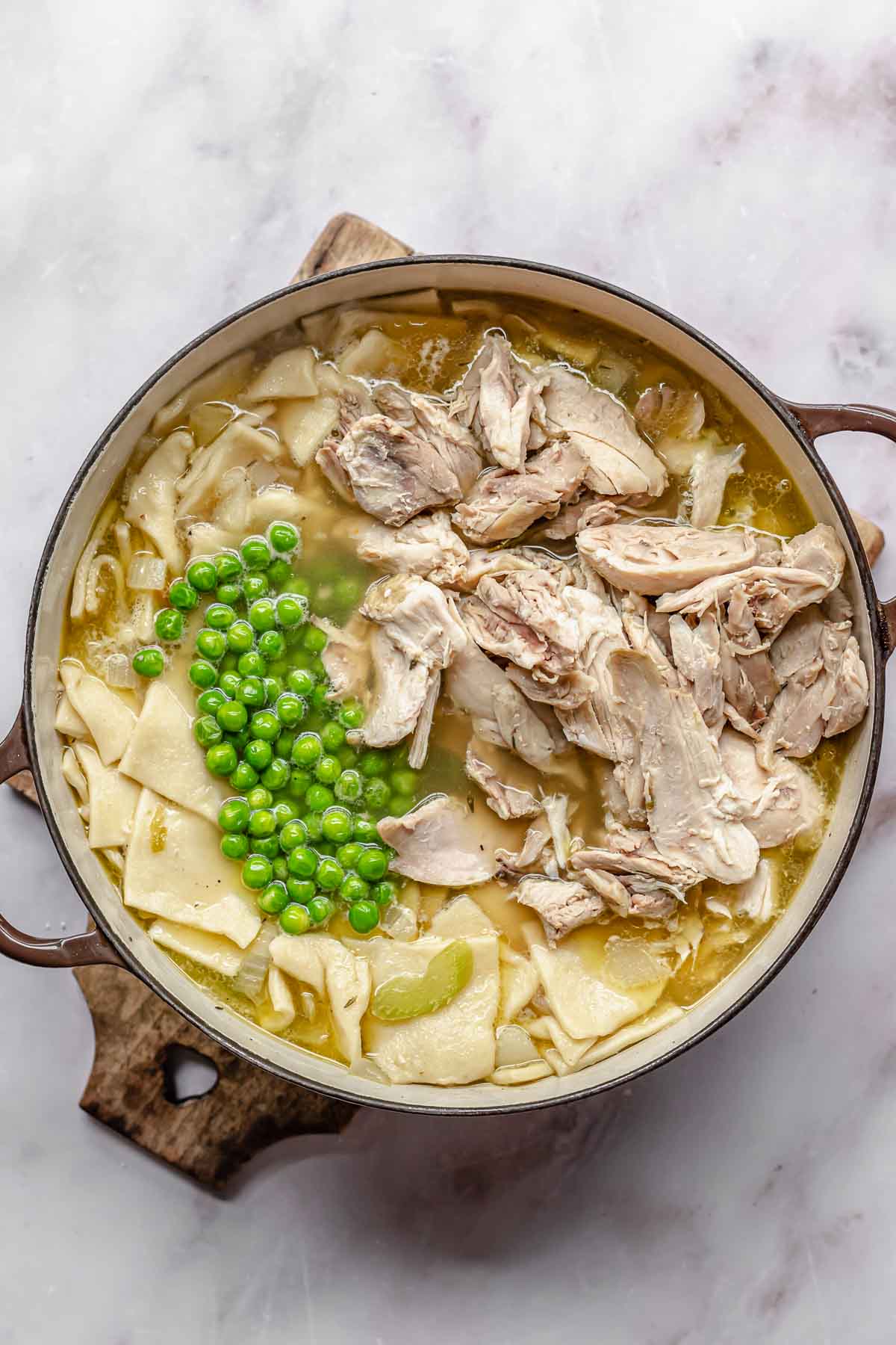 Peas and chicken on top of chicken soup and noodles.