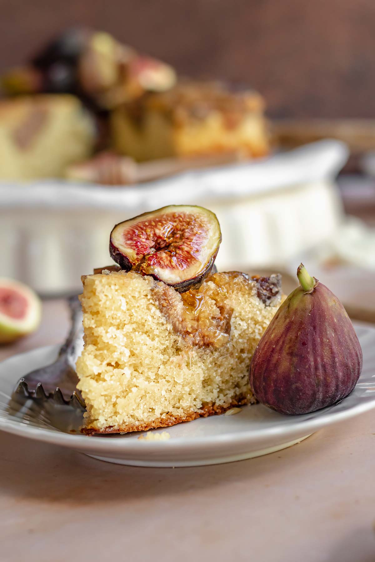 Fig cake on a plate with a fig on top and fork next to it.