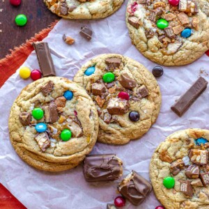Leftover halloween candy cookies on parchment paper with candy pieces surrounding them.