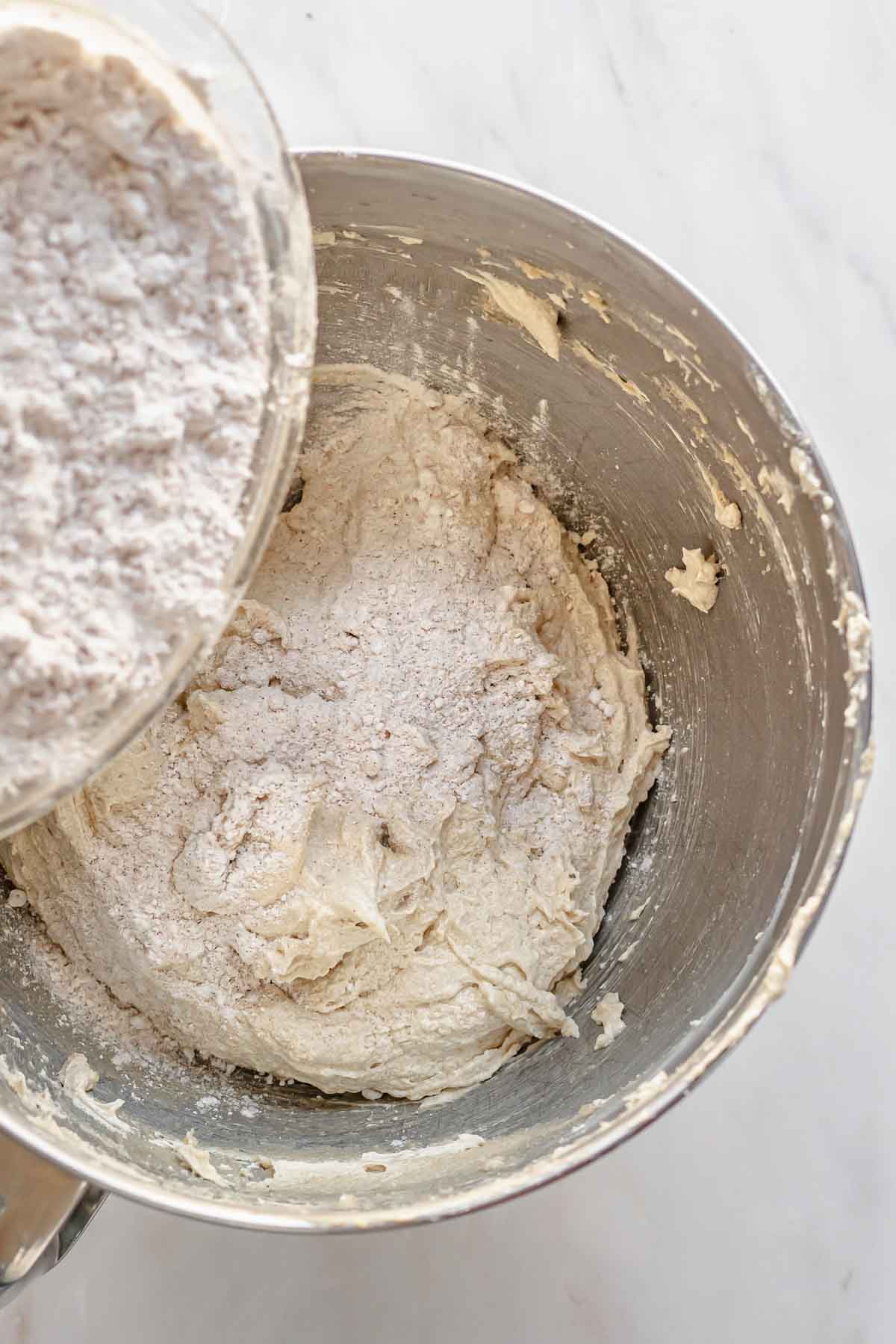 Flour being poured into wet cake batter.