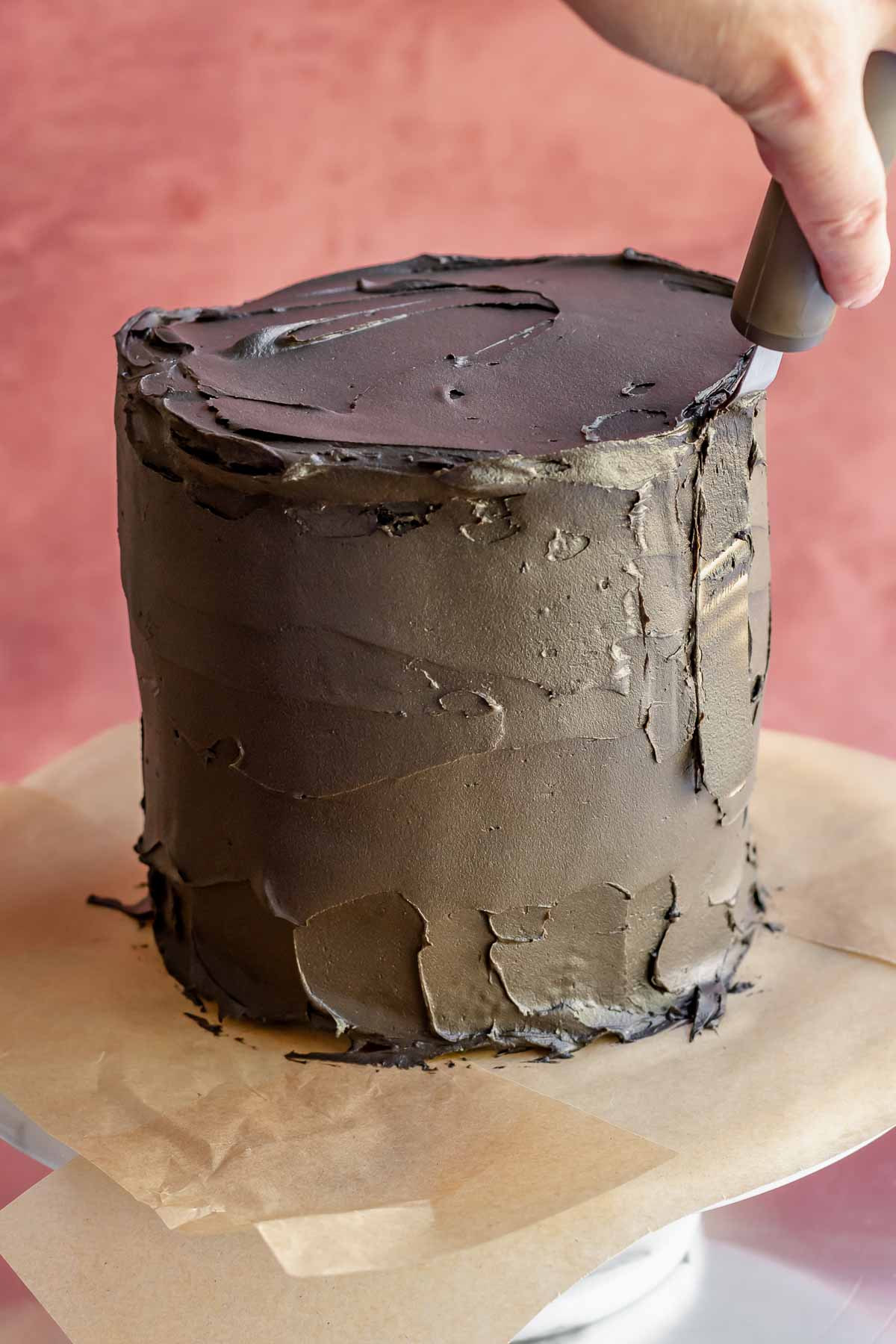 An offset spatula smooths frosting o the side of the cake.