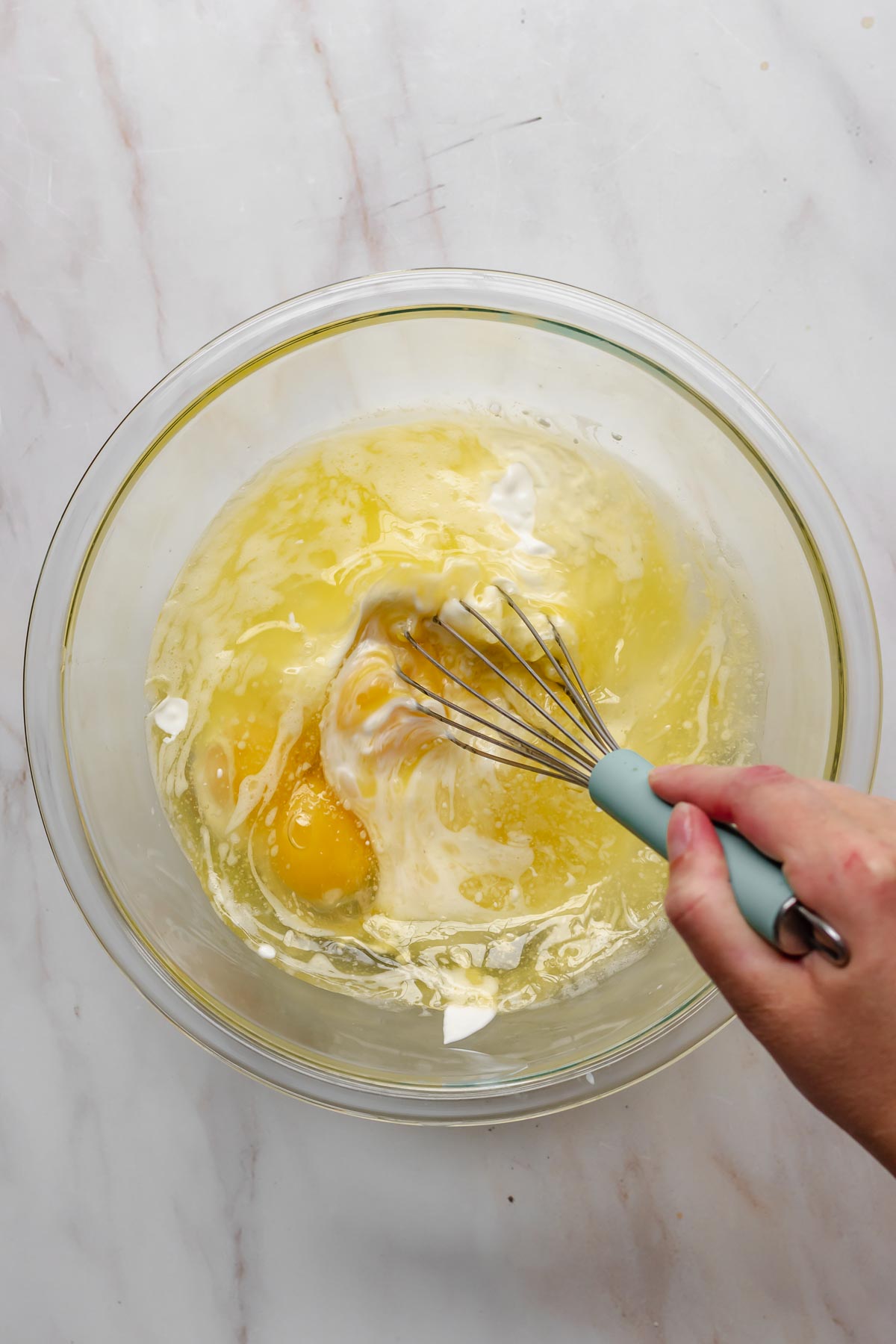 A whisk mixes wet ingredients in a bowl.