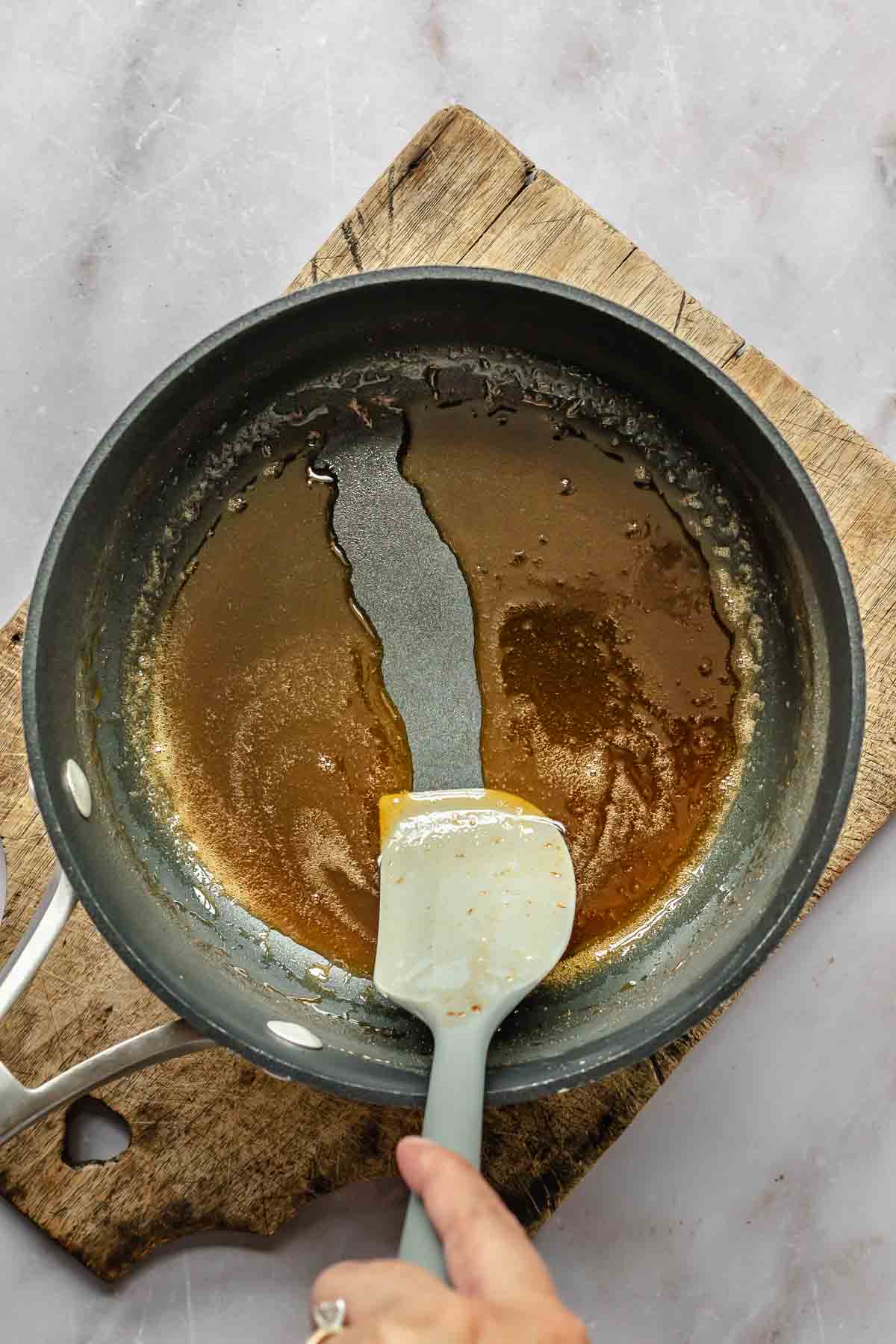 A spatula runs through liquid in a pot.