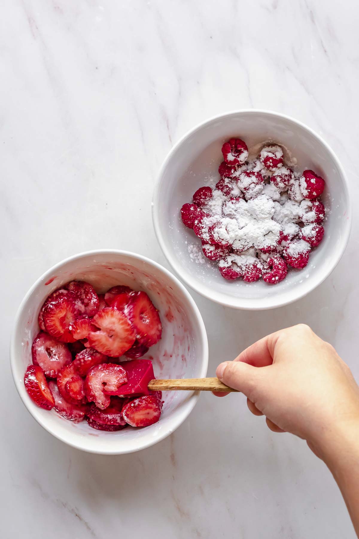 A spatula mixes fruit and cornstarch in bowls.