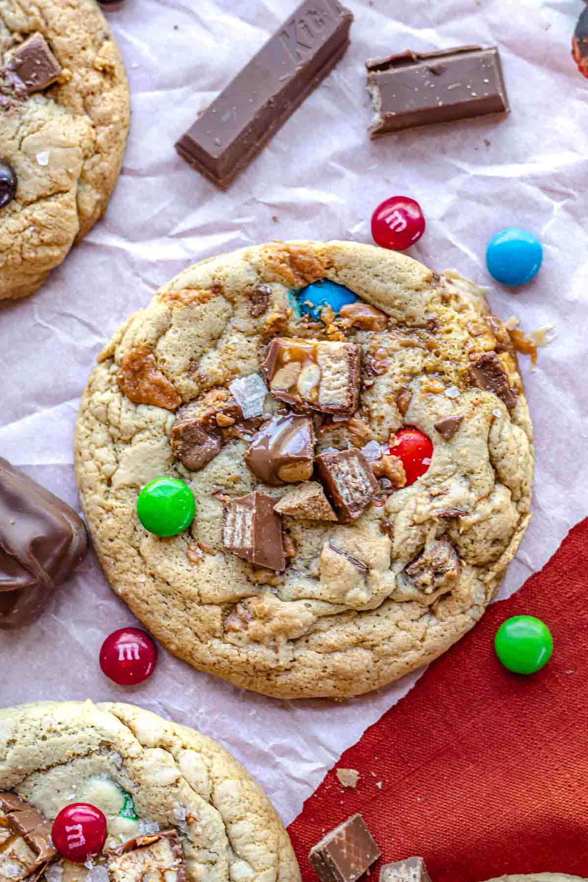 One halloween candy cookie with candy pieces scattered around.