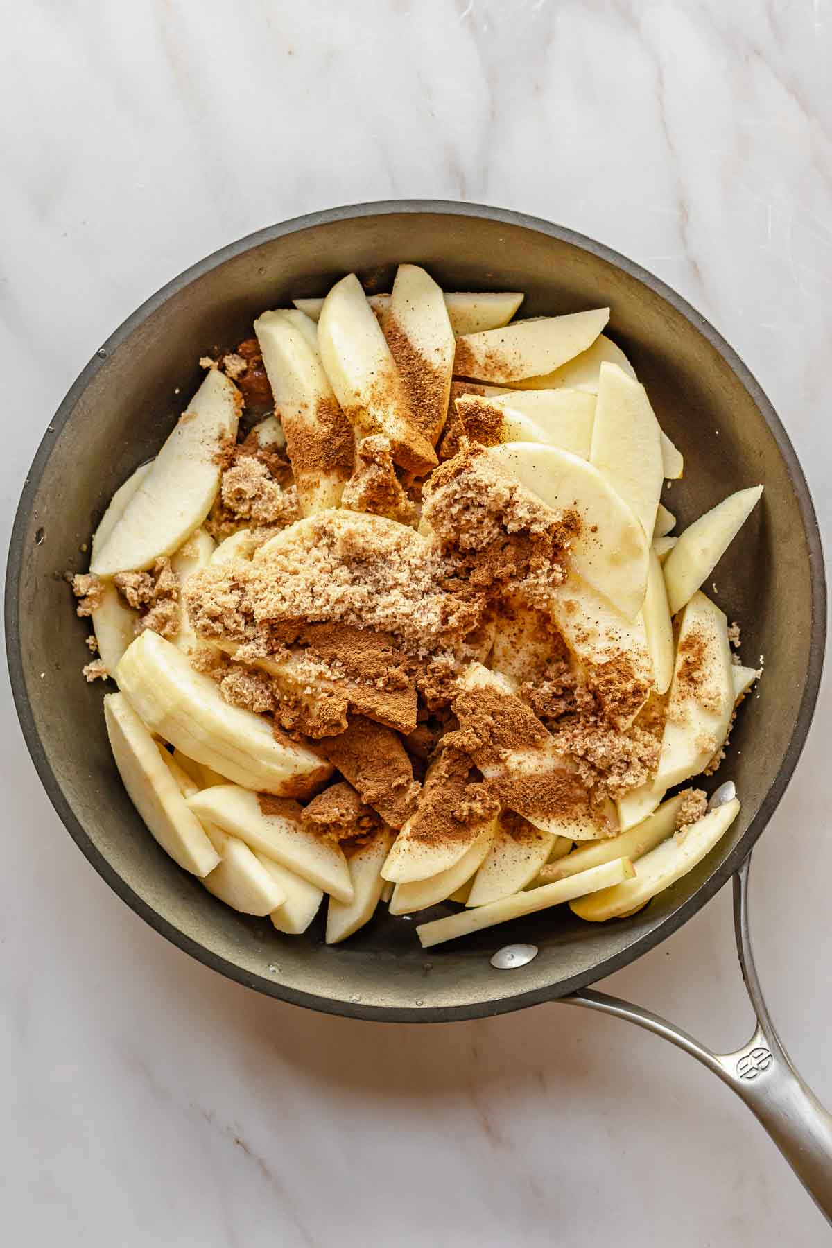 Apples, sugar, and spices in a pan.