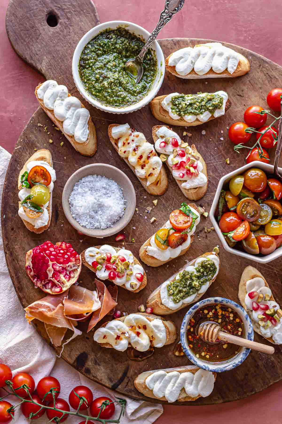 An arrangement of whipped ricotta crostini on a board with fixings.