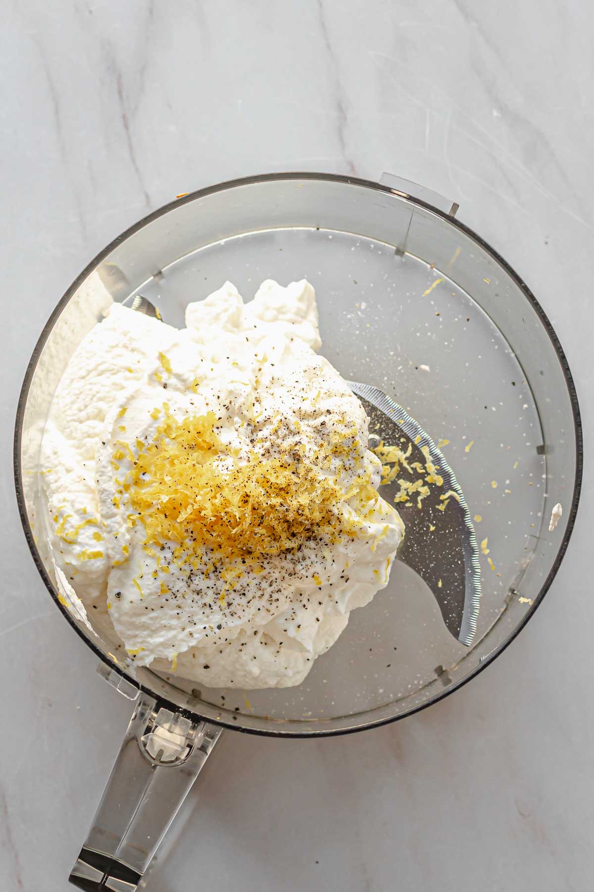 Ricotta cheese, lemon zest, salt and pepper in a food processor bowl.