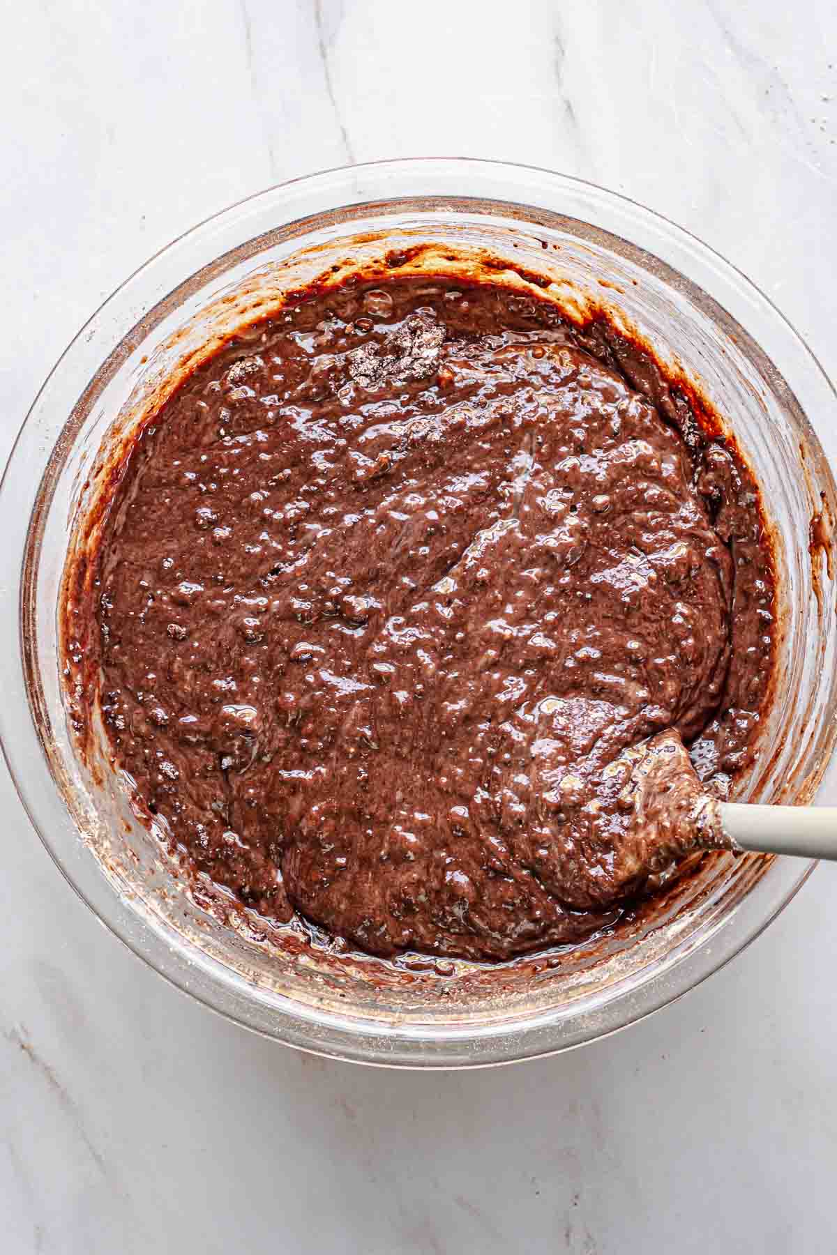A spatula mixes together the chocolate cake batter.