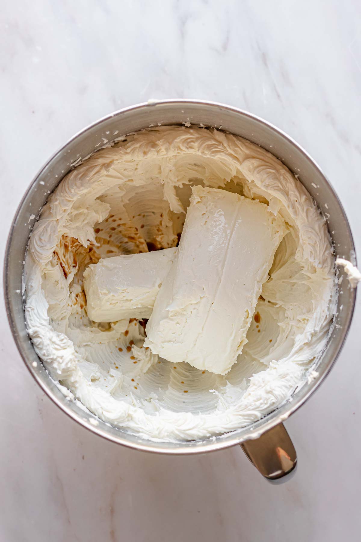 Whipped butter and sugar in a bowl with two bricks of cream cheese.