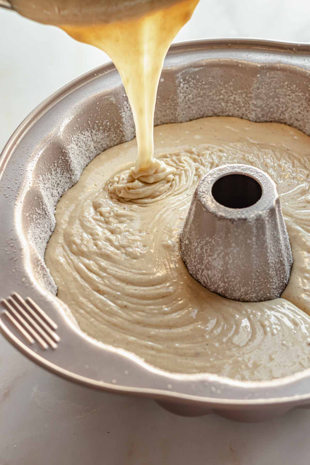 Eggnog cake batter being poured into a bundt pan.