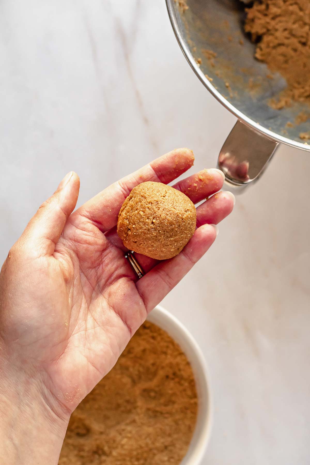 Rolled graham cracker cookie dough ball in a hand.