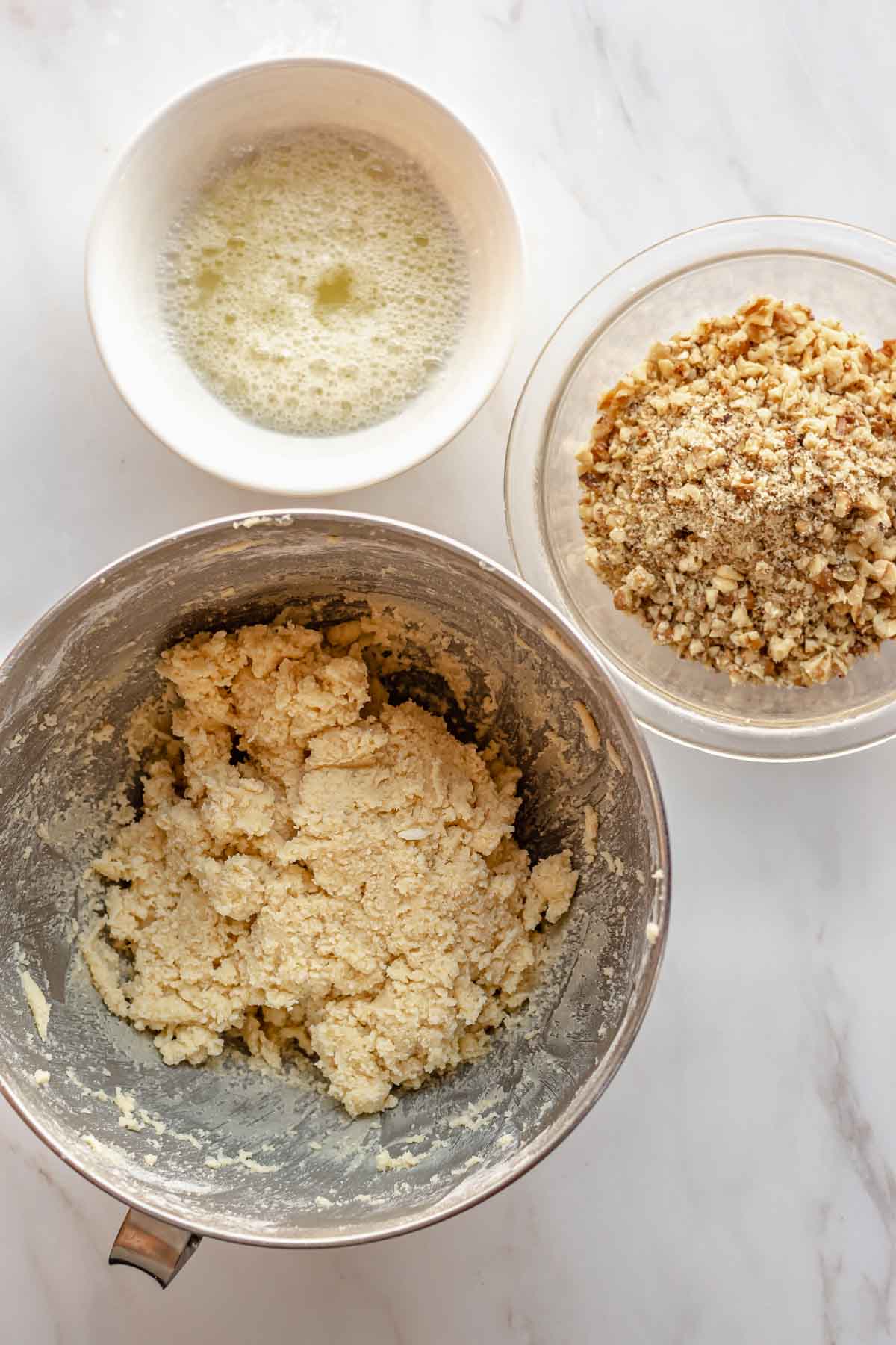 Dough, chopped walnuts, and egg whites in separate bowls.