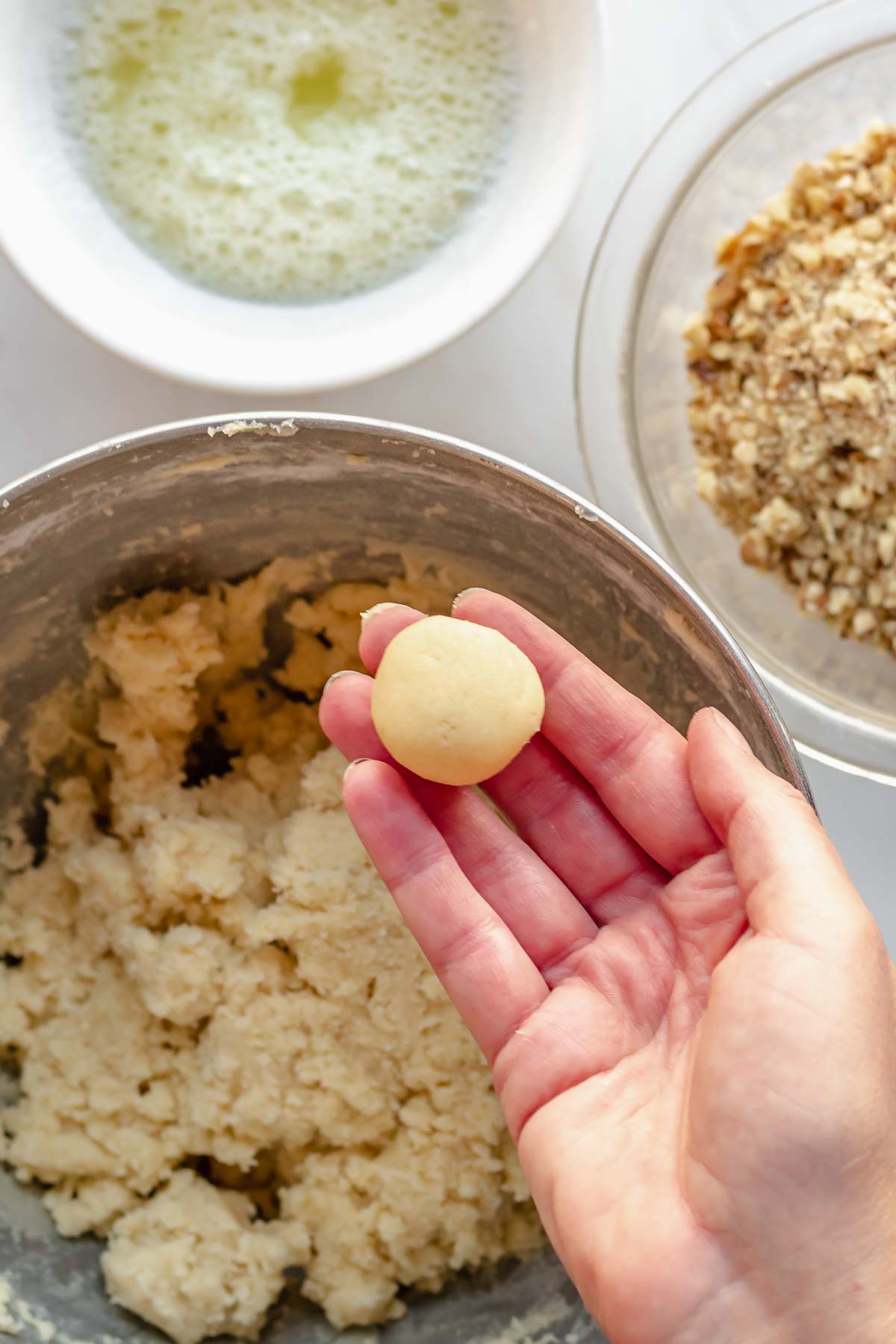 A rolled cookie dough ball in a hand.