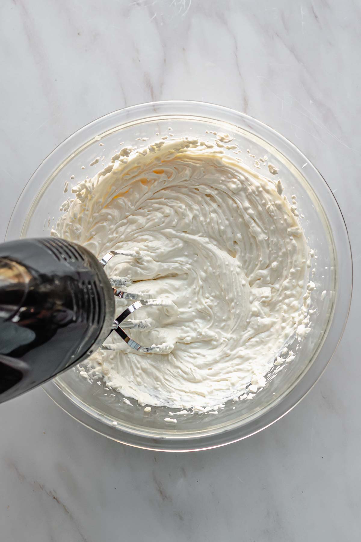 A hand mixer mixes together the wet ingredients in a bowl.