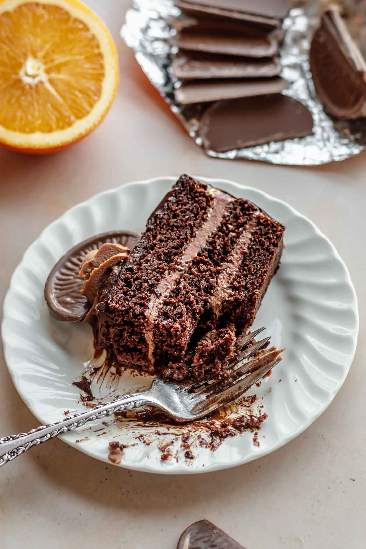 Slice of chocolate orange cake on a plate with a fork and bite removed.