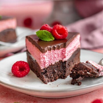Piece of chocolate raspberry cake on a plate with a bite removed.
