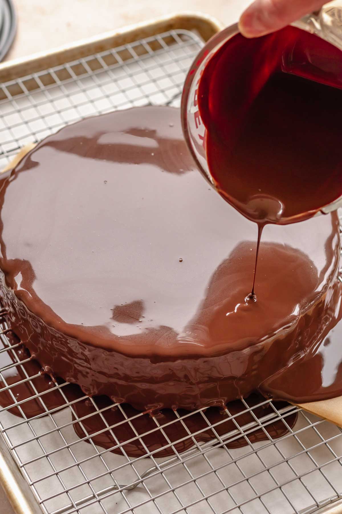 Chocolate ganache being poured over the cake.