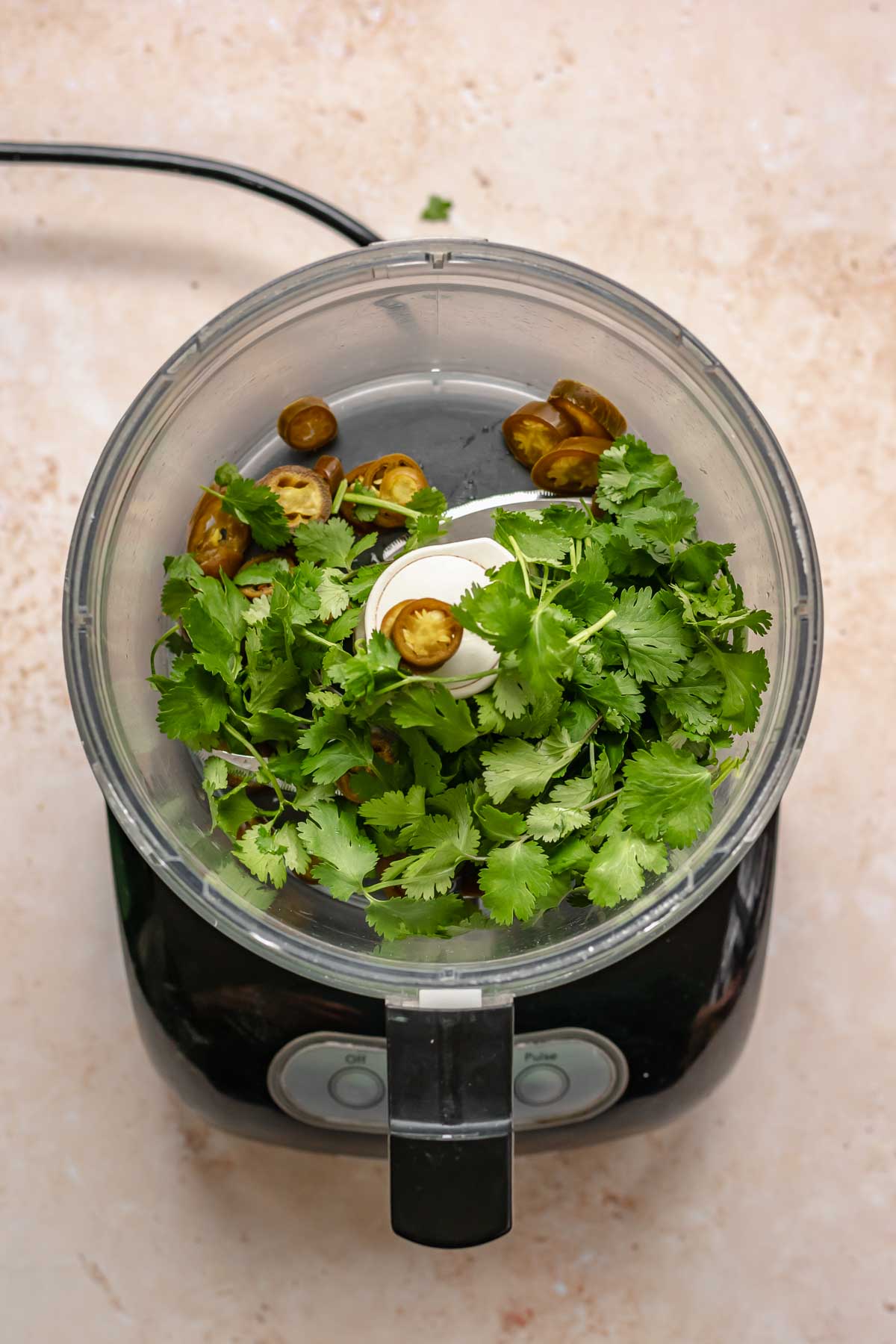 Cilantro and pickled jalapeños in a food processor.