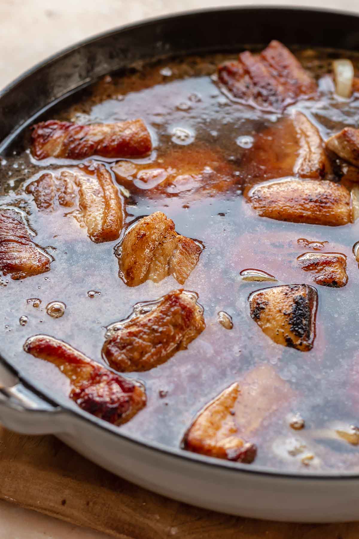 Pork belly in a pot with braising liquid.