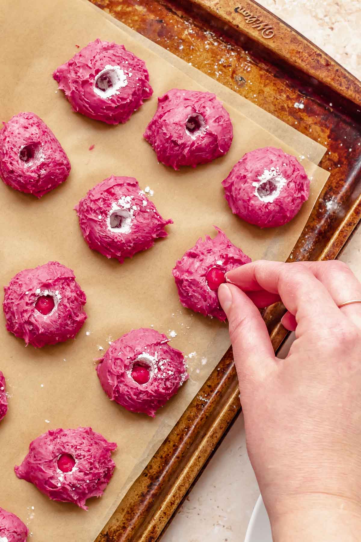 A hand adds frozen dollops of raspberry puree into each candy.
