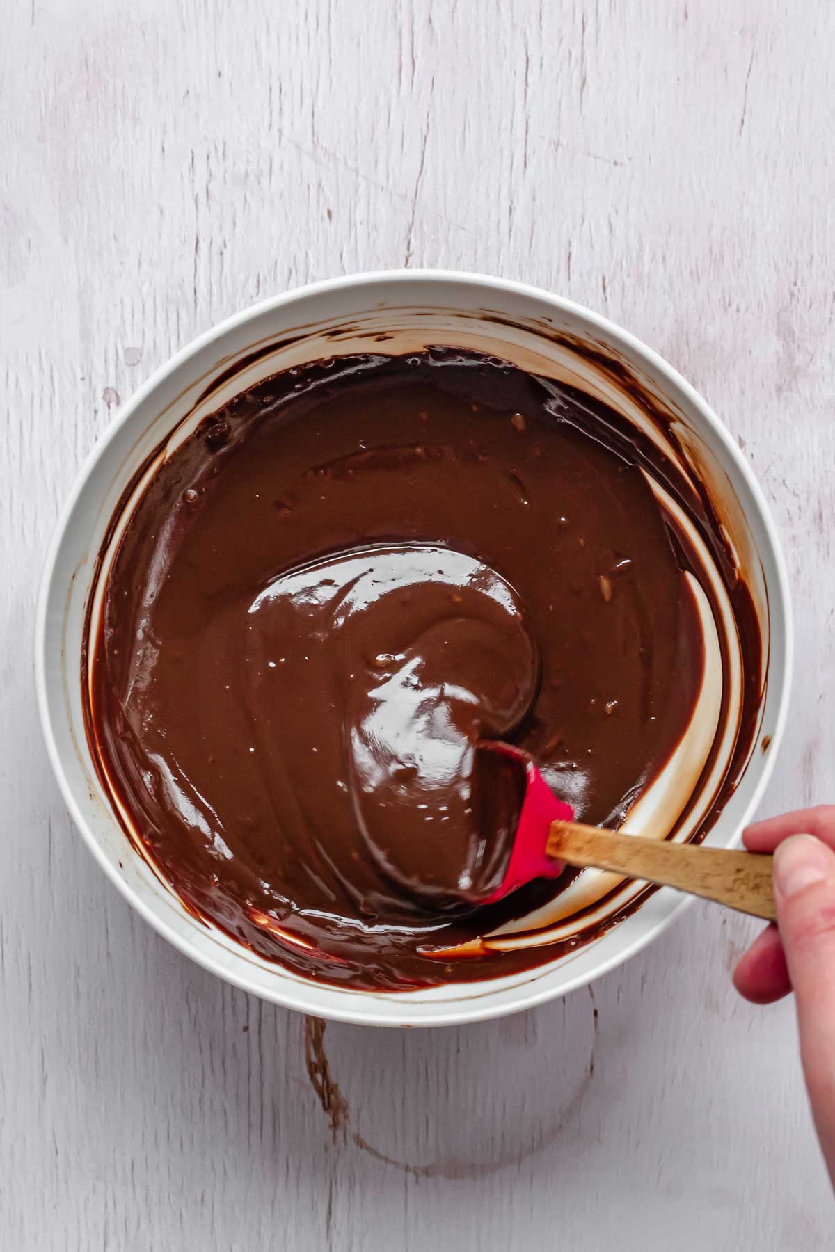 A mini spatula mixes together smooth chocolate ganache.